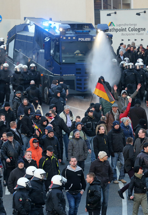 Police drive back right-wing demonstrators using a water cannon during protests in Cologne, Germany on Saturday (Roland Weihrauch/dpa via AP)
